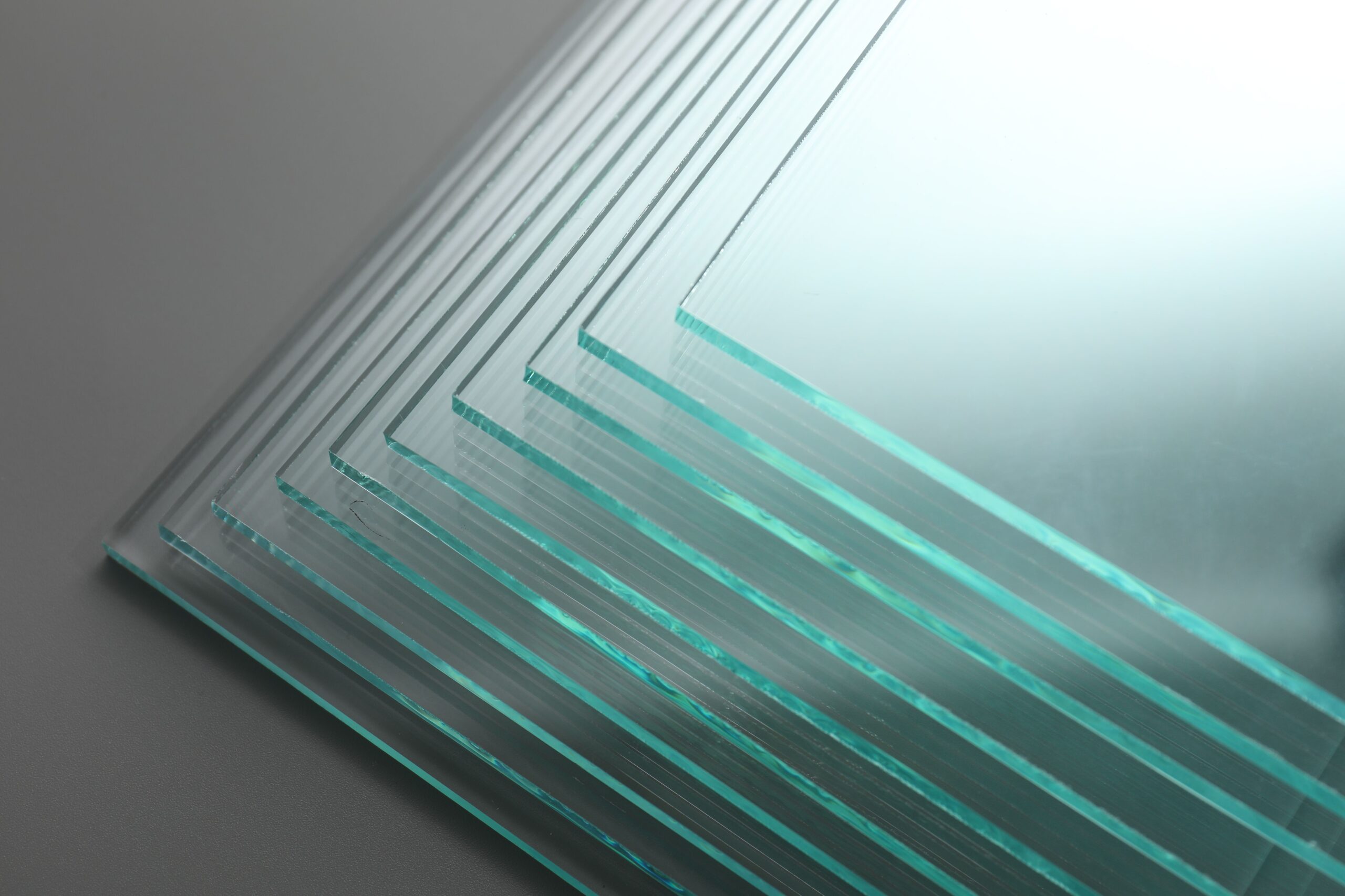 Stack of glass sheets on grey background, closeup